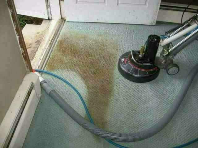 Professional carpet cleaning machine in action on stained beige carpet